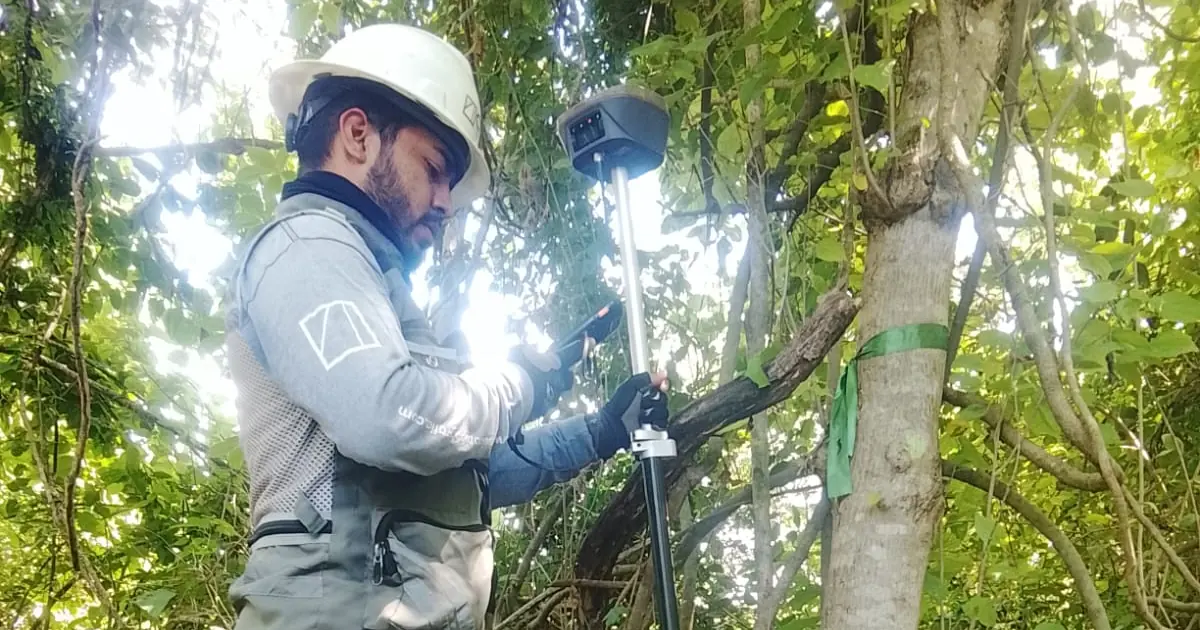Topógrafo con receptor GNSS RTK bajo vegetación revisando la solución en el colector