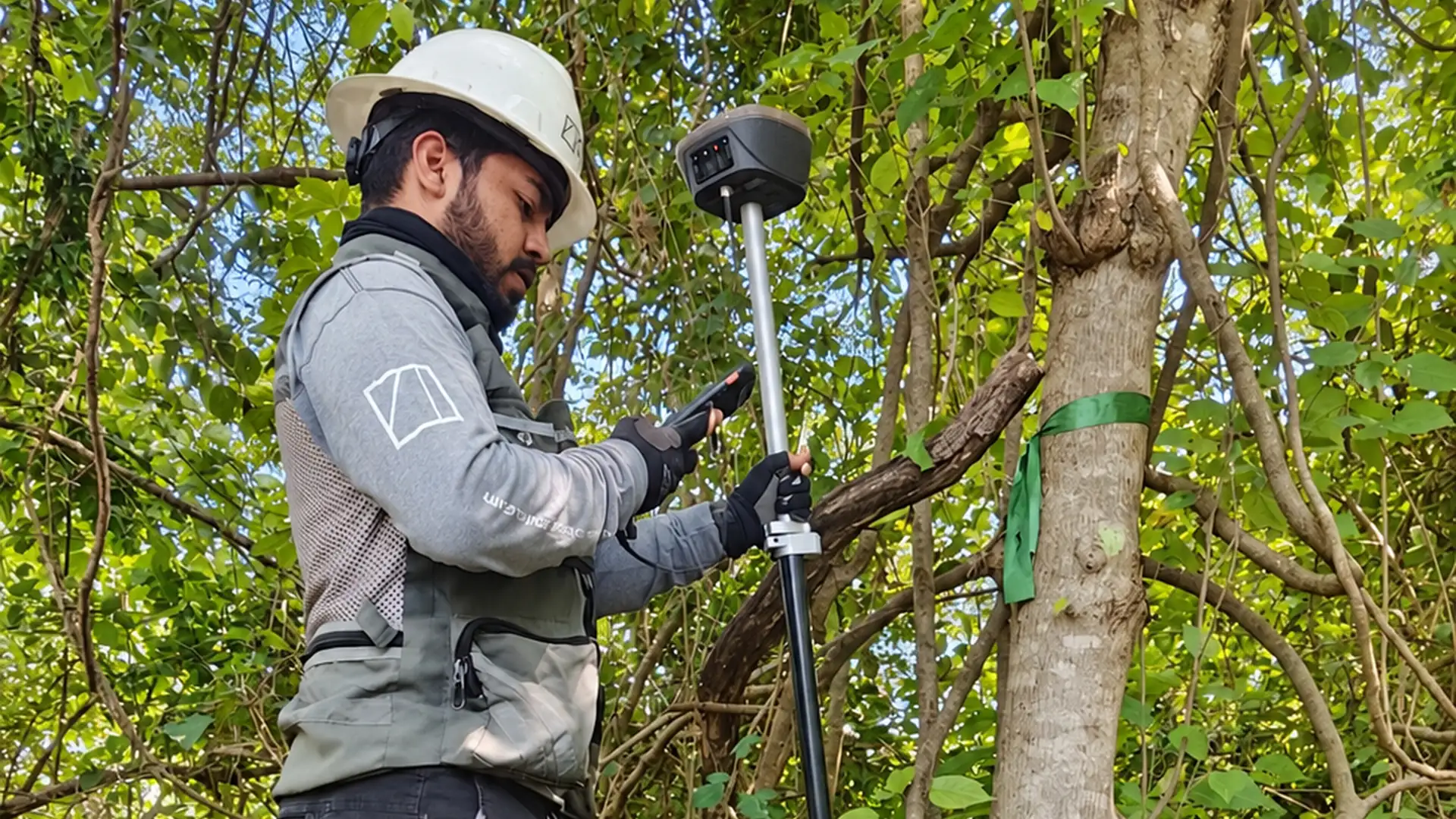 Topógrafo de CISA revisando el colector junto a un receptor GNSS RTK bajo vegetación densa